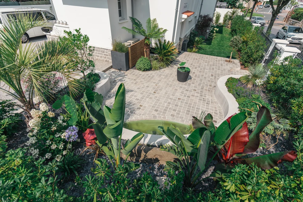 Aménagement paysager : vue aérienne d'une terrasse en pavés entourée de plantes tropicales à Biarritz par ADIO.