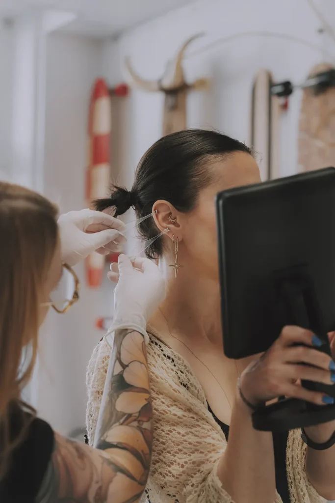 Événement piercing : Une cliente découvre son nouveau bijou Buddha Jewelry dans le miroir chez Vauban Piercing & Tattoo à Bayonne, photo par l'agence ADIO.