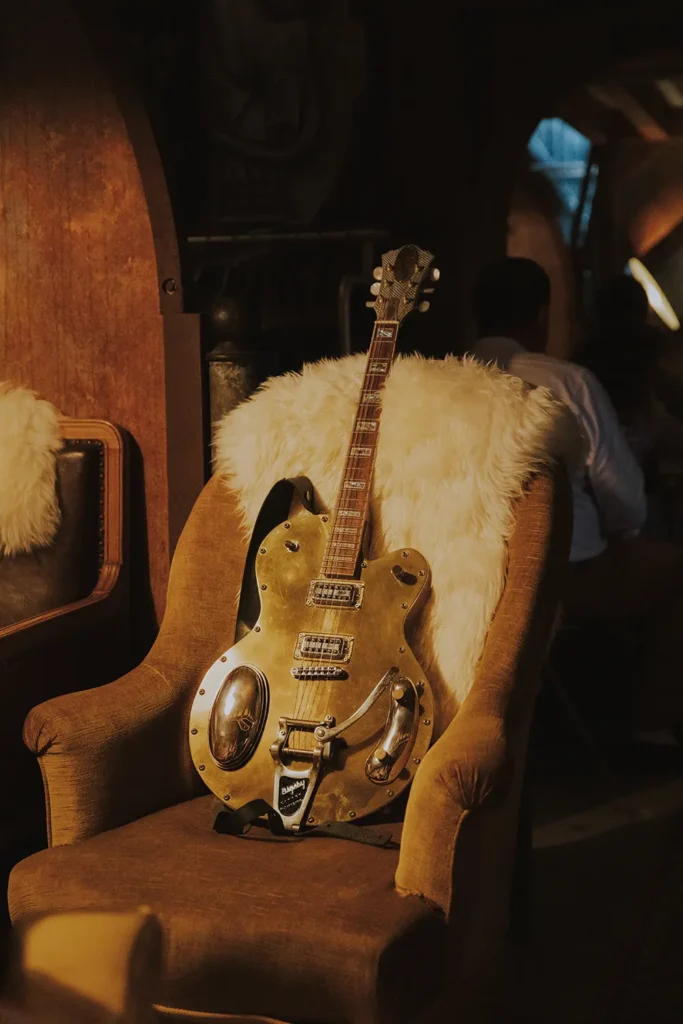 Photographe d'ambiance : une vieille guitare électrique vintage posée sur un fauteuil ancien au Prohibido Jazz Club à Biarritz par Studio Adio.