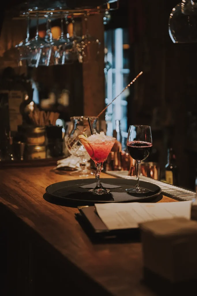Photographe de cocktail : verre de cocktail rouge avec glace pilée et tranche de citron sur le comptoir du Prohibido Jazz Club à Biarritz par Studio Adio.