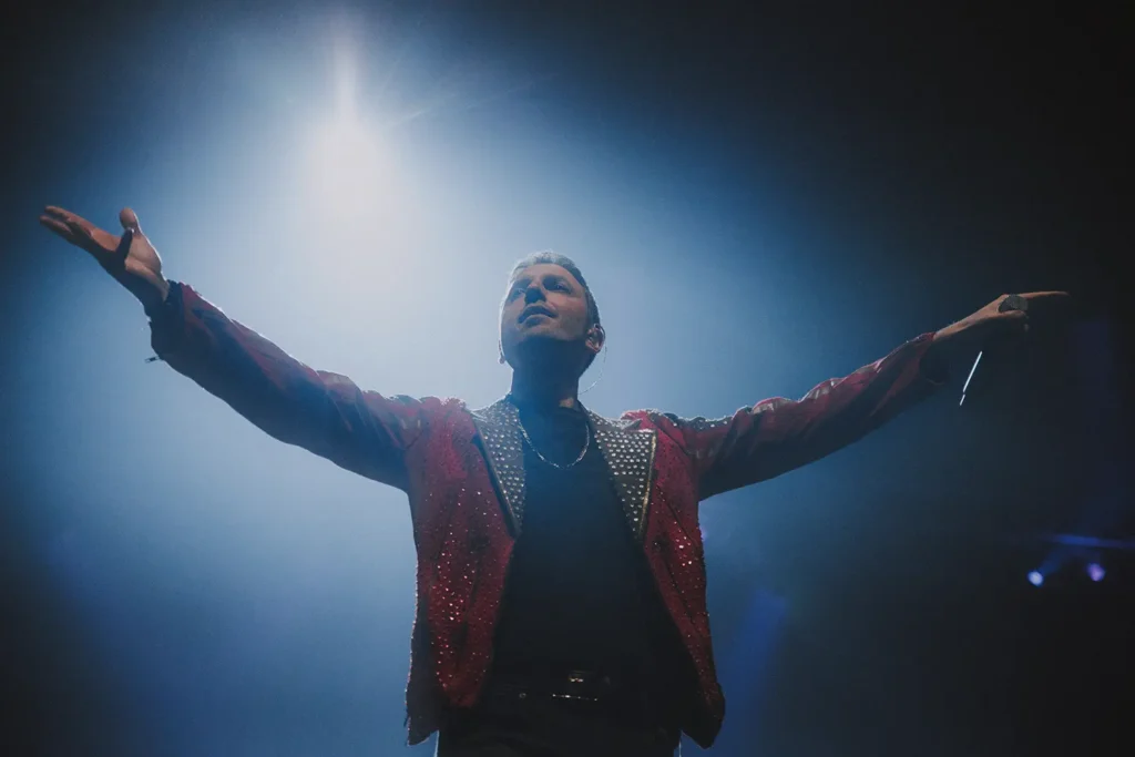 Concert : Fred Caramia en veste rouge scintillante chantant à l'Arkéa Arena capté par ADIO