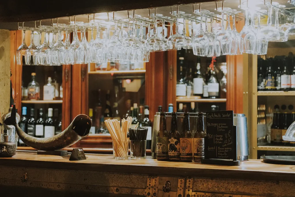 Photographe d'intérieur : comptoir en couleur avec verres suspendus, pierres et décoration au Prohibido Jazz Club à Biarritz par Studio Adio.