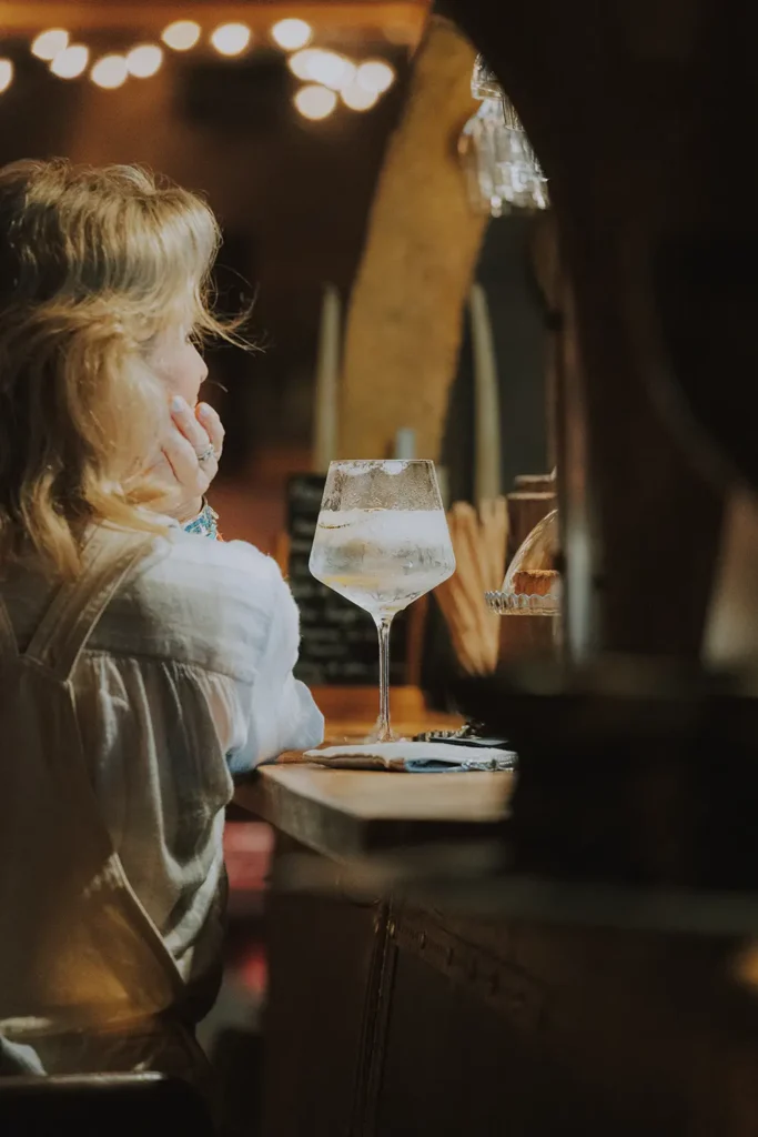Photographe lifestyle : une femme de dos avec son verre frais posé sur le comptoir du Prohibido Jazz Club à Biarritz par Studio Adio.