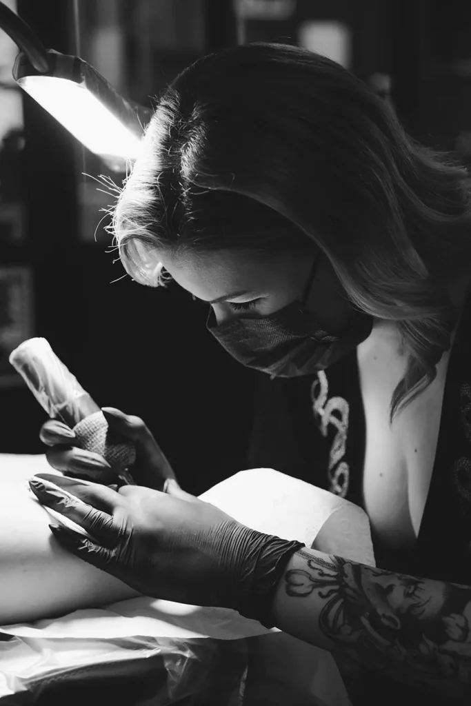 Photo noir et blanc : Concentration de l'artiste réalisant un tatouage avec précision chez Hamsaran Tattoo à Bayonne, par l'agence ADIO.