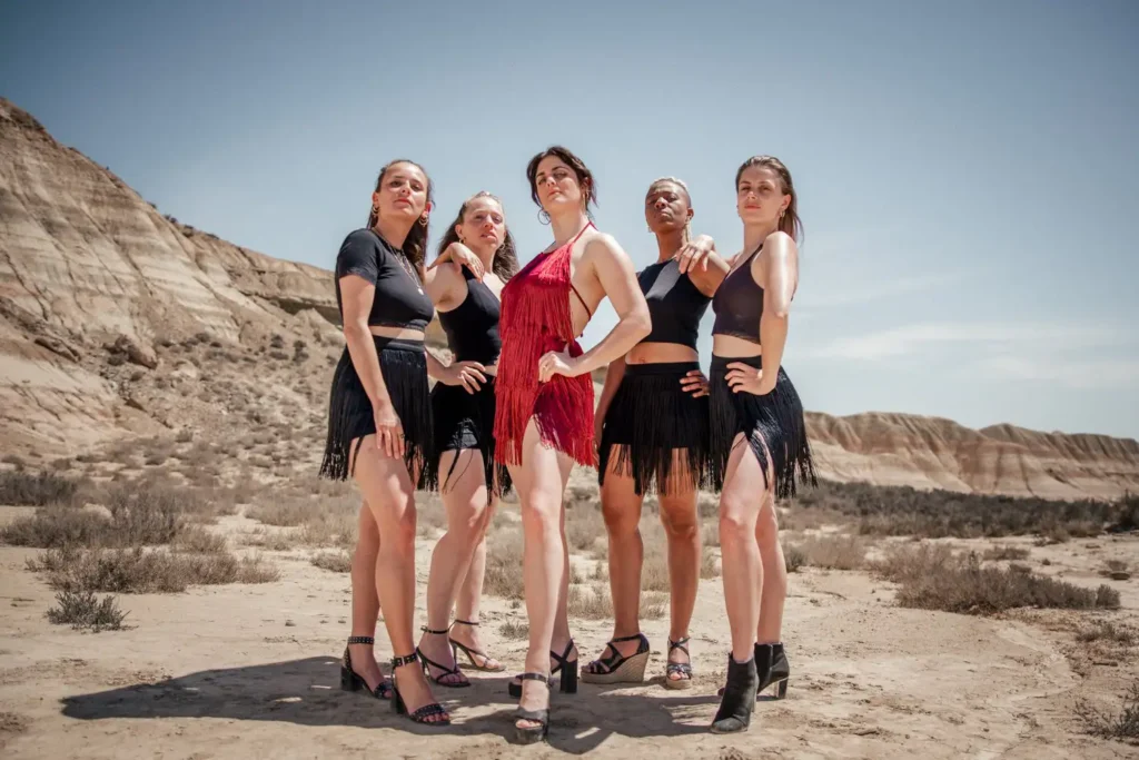 Photos des backstage : Victoria Picone en rouge et ses danseuses posant en contre-plongée aux Bardenas pour ADIO.