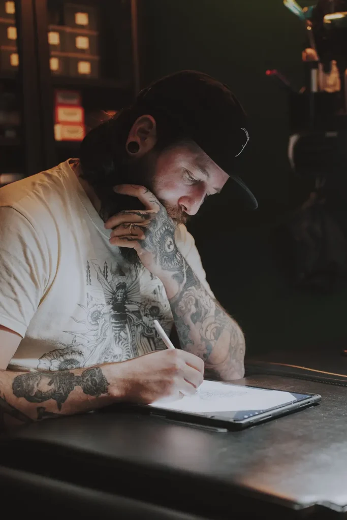 Reportage créatif : Le tatoueur travaille sur un projet de dessin numérique sur tablette chez Hamsaran Tattoo à Bayonne, par l'agence ADIO.