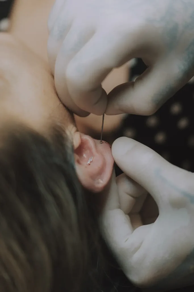 Reportage photo : Gros plan sur l'insertion précise d'un piercing au cartilage chez Vauban Tattoo à Bayonne par l'agence ADIO.