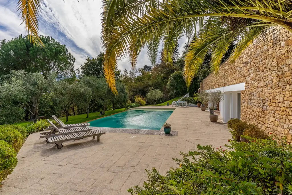 Reportage photo immobilier : piscine chauffée et transats sous les palmiers pour Sotheby's au Pays Basque par ADIO.