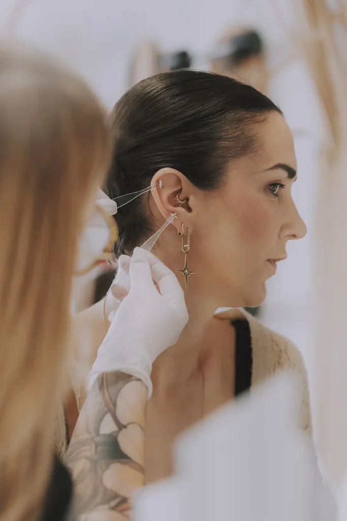 Reportage photo : Plan rapproché sur la pose d'un bijou d'oreille lors de l'événement Buddha Jewelry chez Vauban Piercing à Bayonne, capturé par l'agence ADIO.
