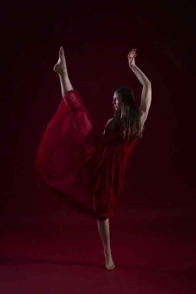 Shooting photo d'une danseuse en robe rouge avec pose de yoga sur fond rouge par Studio Adio.