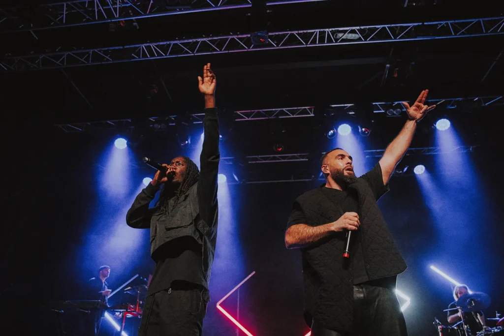 Reportage événementiel : Médine et son musicien haranguent la foule sous des lumières bleues et rouges à l'Atabal par l'agence ADIO