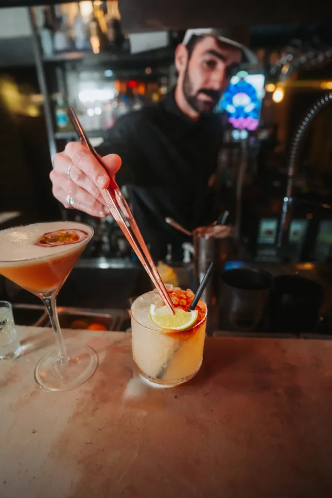Focus mixologie : Barman utilisant une pince pour la finition d'un cocktail au Kubata à Bayonne, capturé par l’agence ADIO