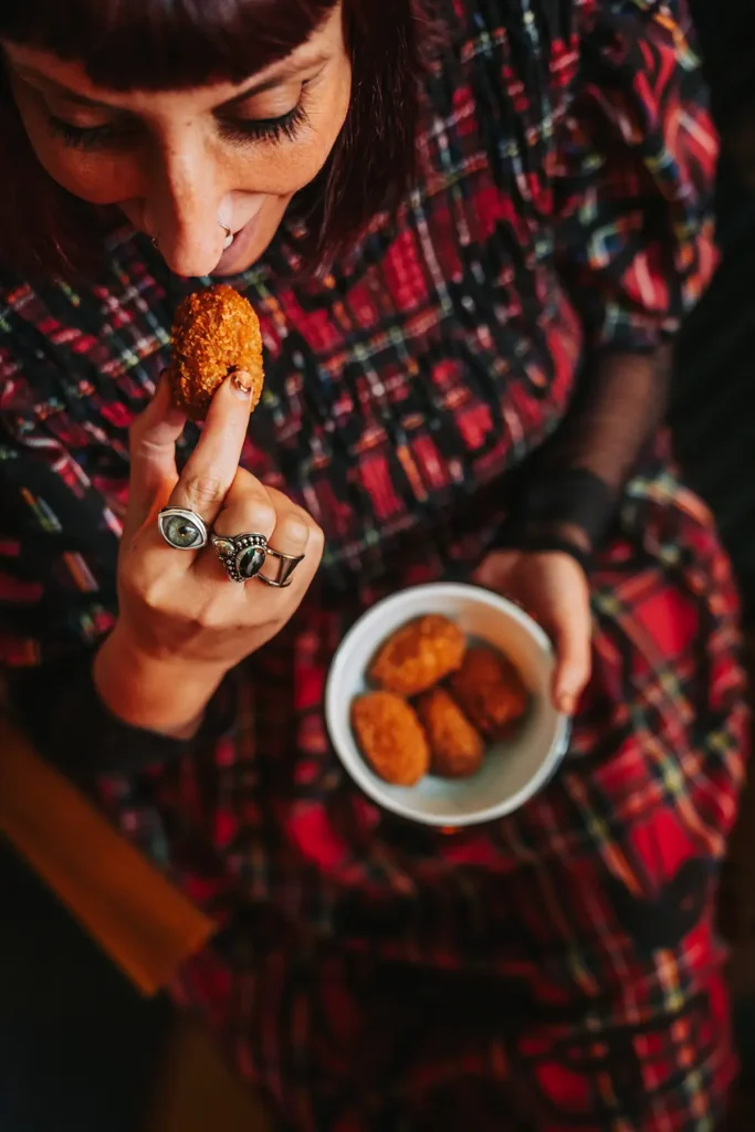 Lifestyle : Vue de haut d'une cliente savourant une croqueta lors d'une soirée au Kubata à Bayonne, image ADIO