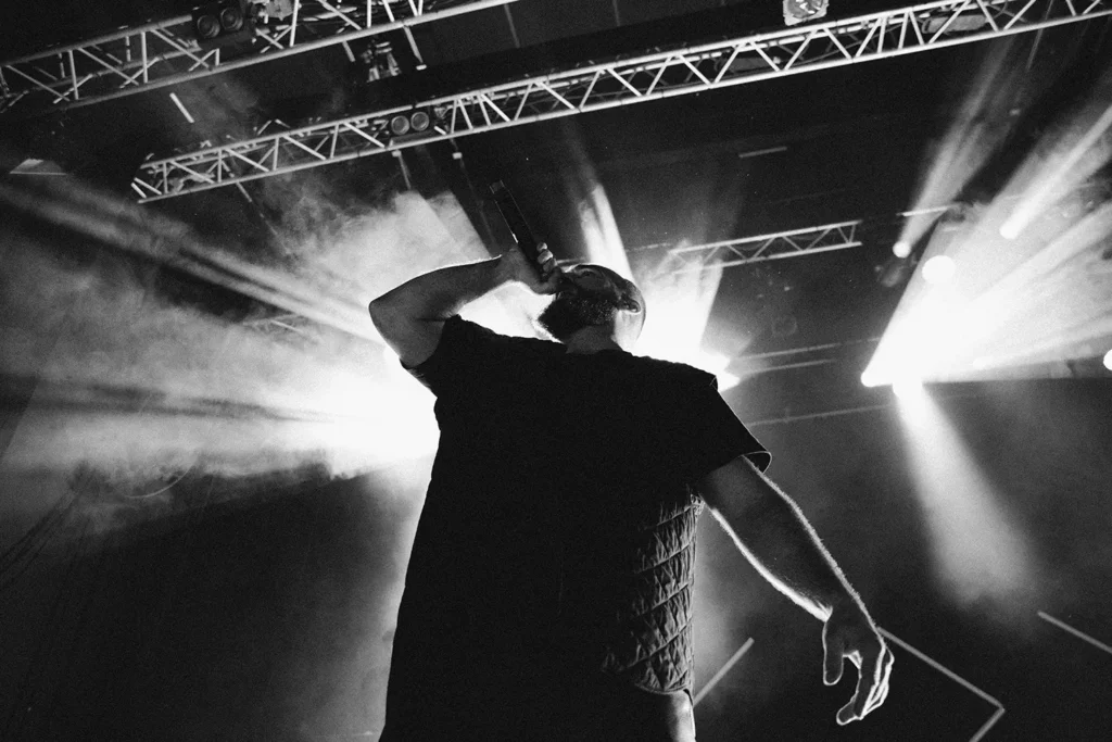 Photographie créative : Contre-plongée artistique de Médine chantant avec des rayons de lumière en contre-jour à l'Atabal par ADIO