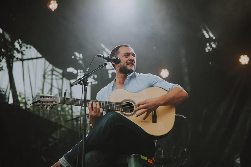 Photo de concert : portrait d'un guitariste chanteur en performance acoustique sur scène au festival Musicalarue capturé par l'agence ADIO