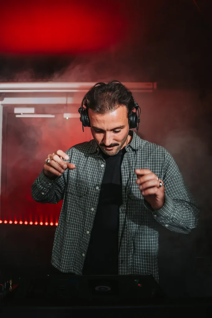 Photographie d'ambiance : DJ concentré sur ses platines avec effets de fumée au Kubata réalisé par l’agence ADIO.