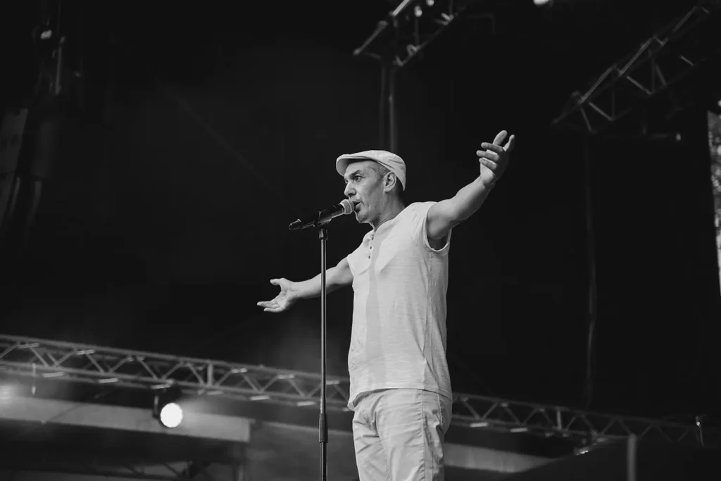 Photographie noir et blanc : chanteur les bras ouverts communiant avec le public de Musicalarue par l'agence ADIO
