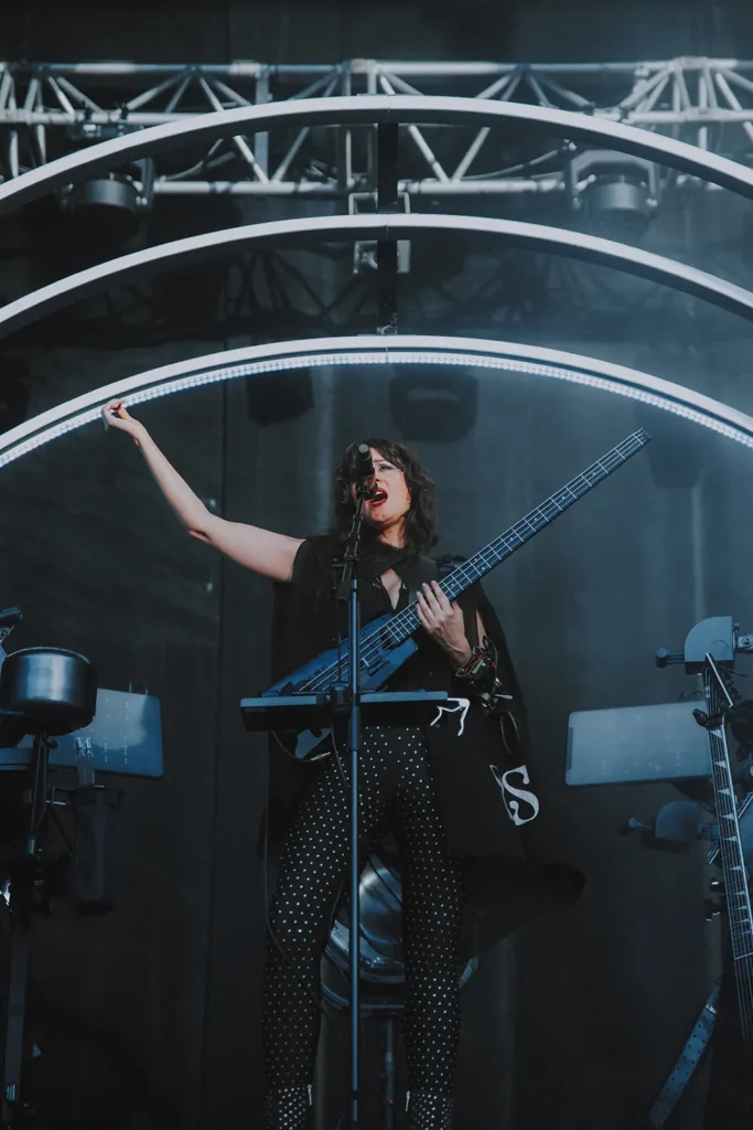 Photographie de scène : musicienne bassiste jouant sous une structure lumineuse moderne lors d'un concert à Musicalarue par l'agence ADIO