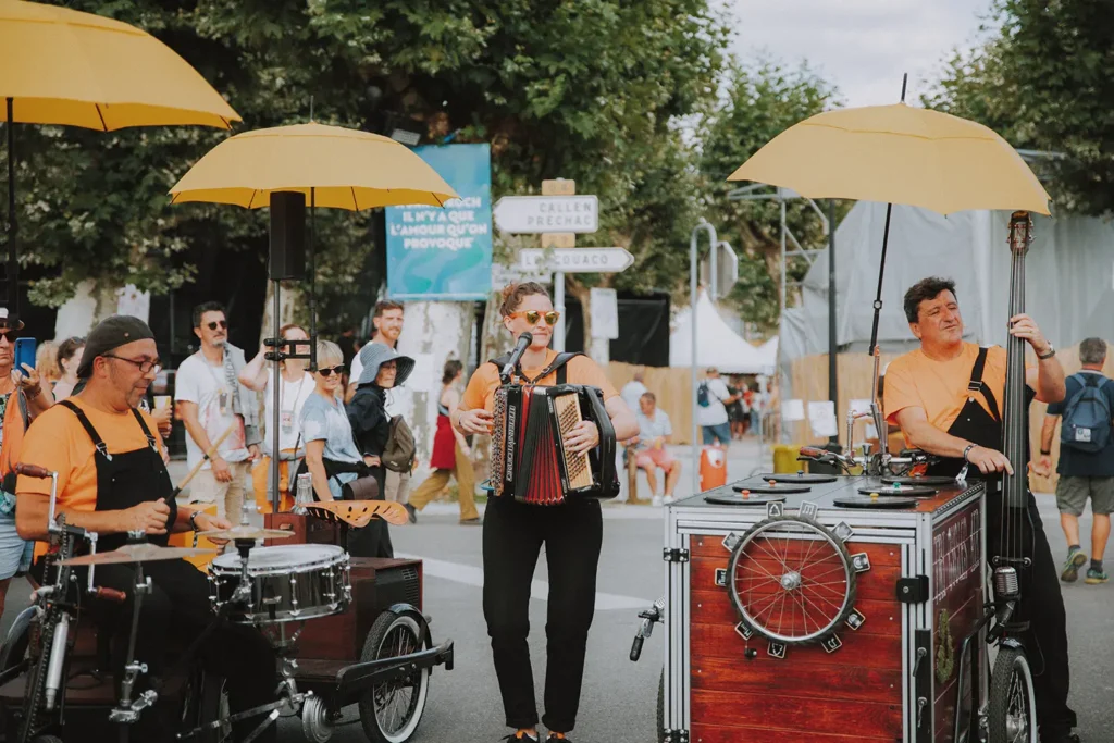 Photographie événementielle : groupe de musique mobile avec instruments originaux et parasols jaunes en déambulation au festival Musicalarue par l'agence ADIO