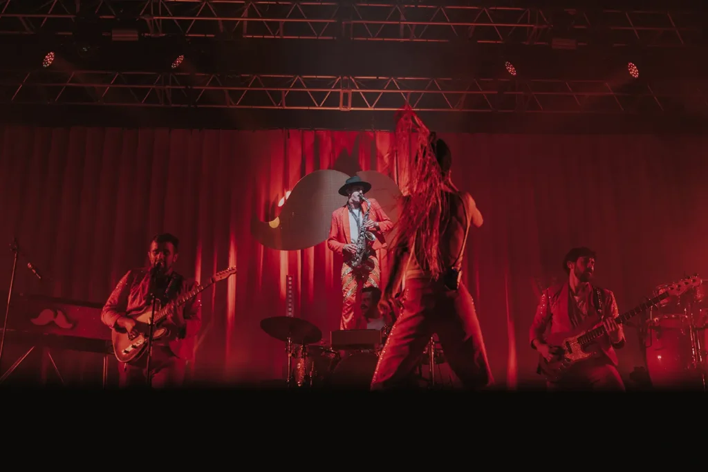 Reportage concert : groupe costumé en rouge performant sous des éclairages dynamiques à Musicalarue par l'agence ADIO