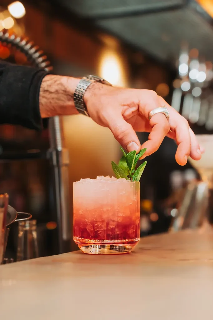 Reportage métier : Geste précis d'un barman ajoutant de la menthe sur un cocktail au Kubata à Bayonne, photo ADIO