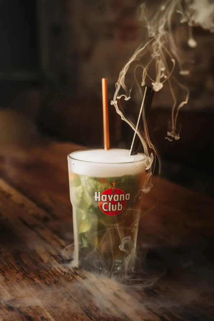 Reportage photo : Cocktail signature fumant servi sur table en bois au bar Kubata à Bayonne, capturé par l'agence ADIO