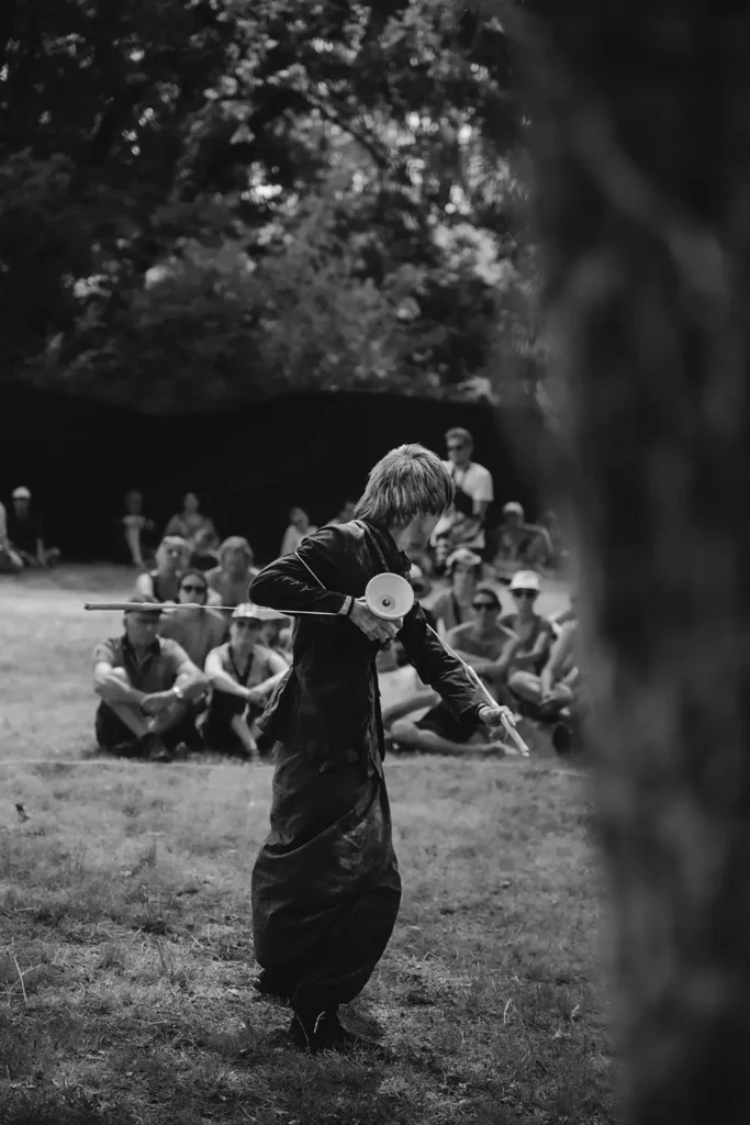 Reportage photo : artiste de rue jonglant avec un diabolo devant un public assis sur l'herbe au festival Musicalarue par l'agence ADIO