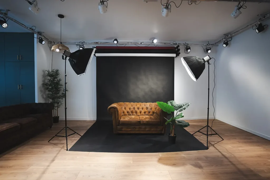 Studio photo : décor avec canapé Chesterfield et plante verte sur fond noir dans le studio ADIO.