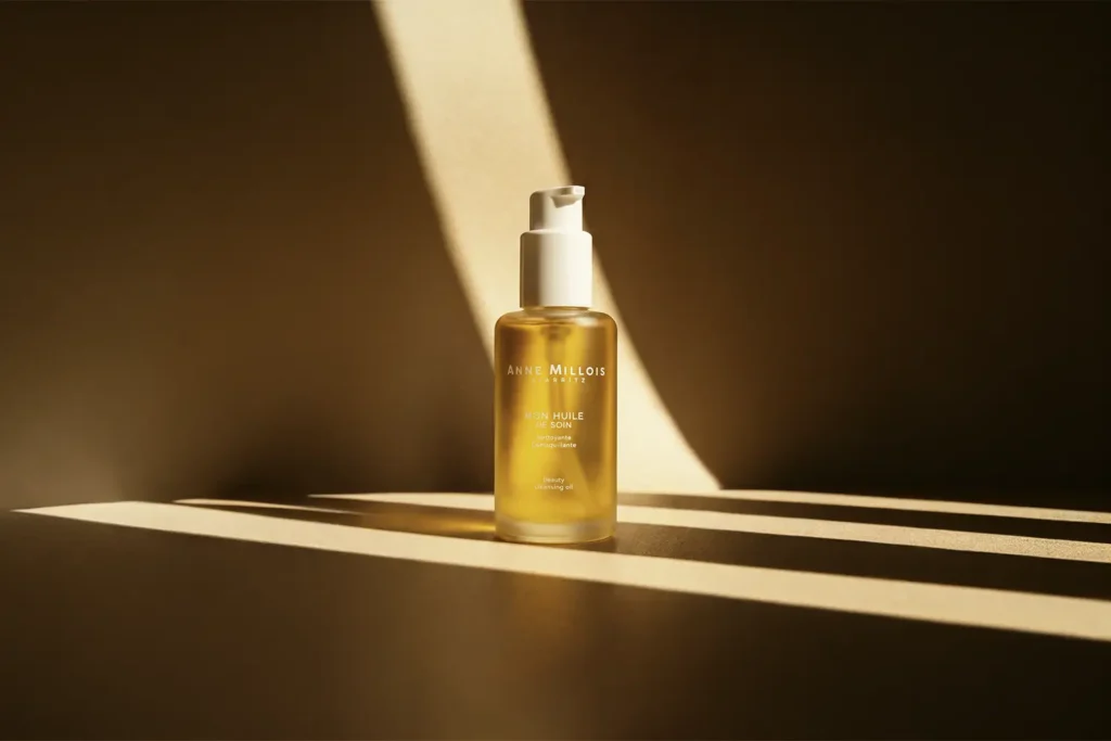 Photographie packshot cosmétique créative de l'Huile de Soin Anne Millois Biarritz, avec jeux d'ombres et lumières chaudes réalisés en studio.