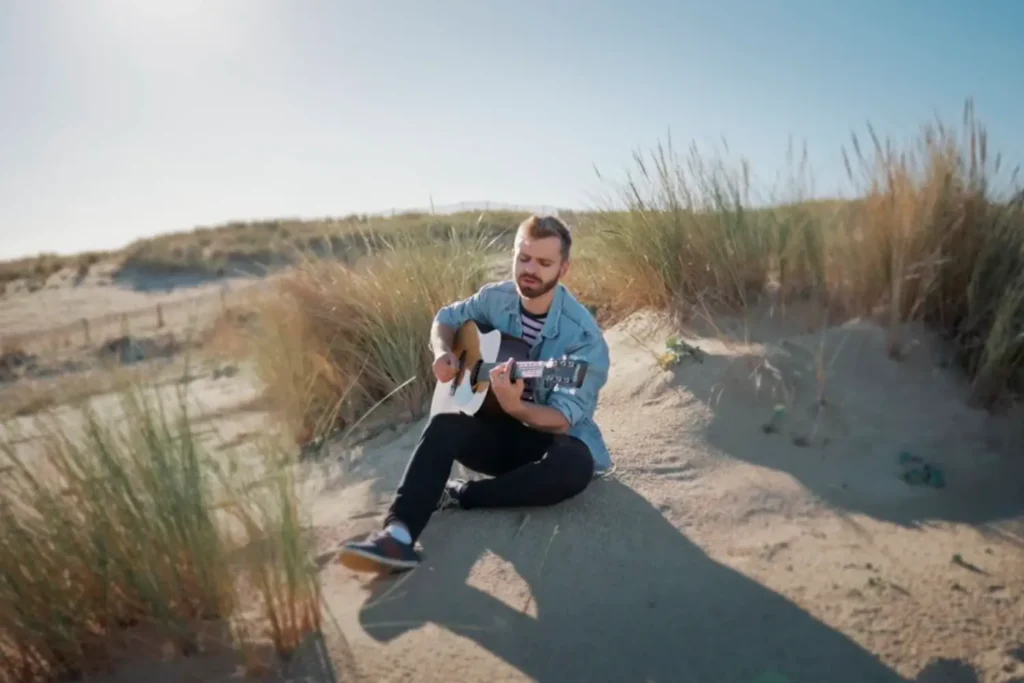 Réalisation de clip : l'artiste Walrus jouant de la guitare dans les dunes par l'agence ADIO.